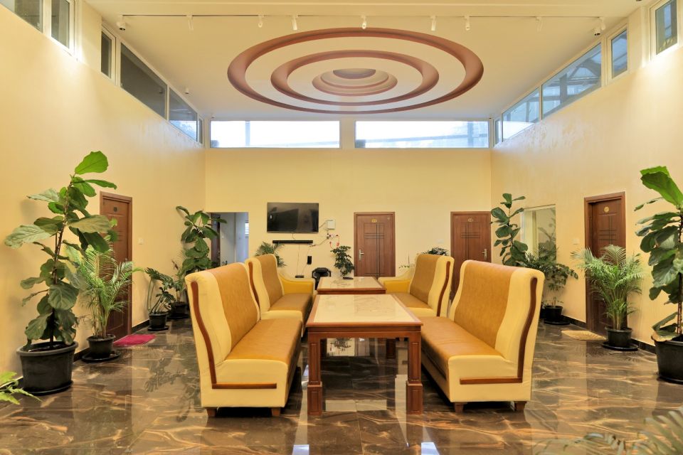 Glass atrium lobby with plants and lounge seating at Sinnis Home Stay