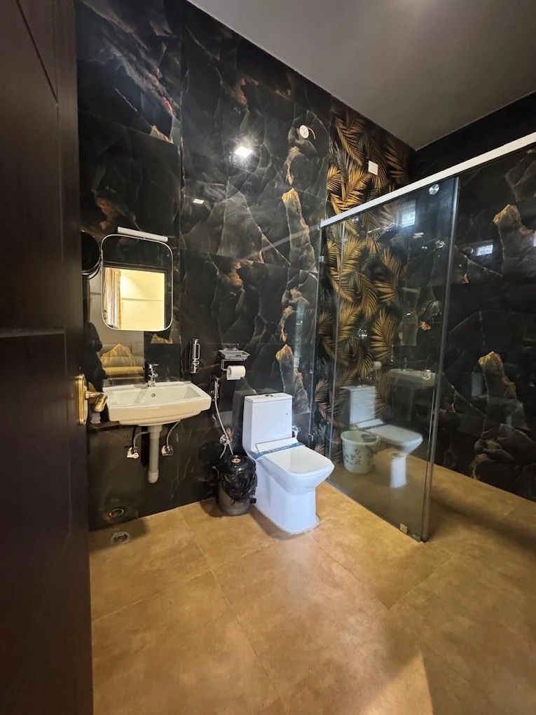 Luxury bathroom in black marble with gold palm motif and glass shower