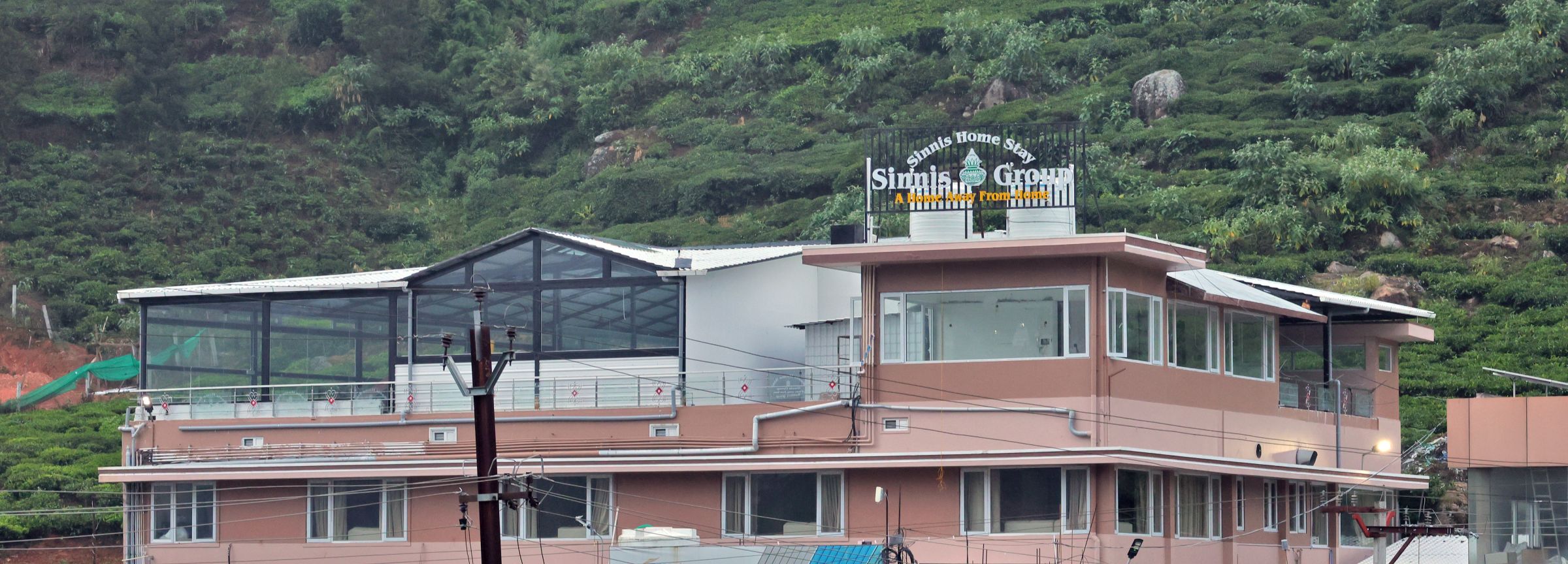 Sinnis Home Stay building on a tea-covered hillside in Kattabettu, The Nilgiris